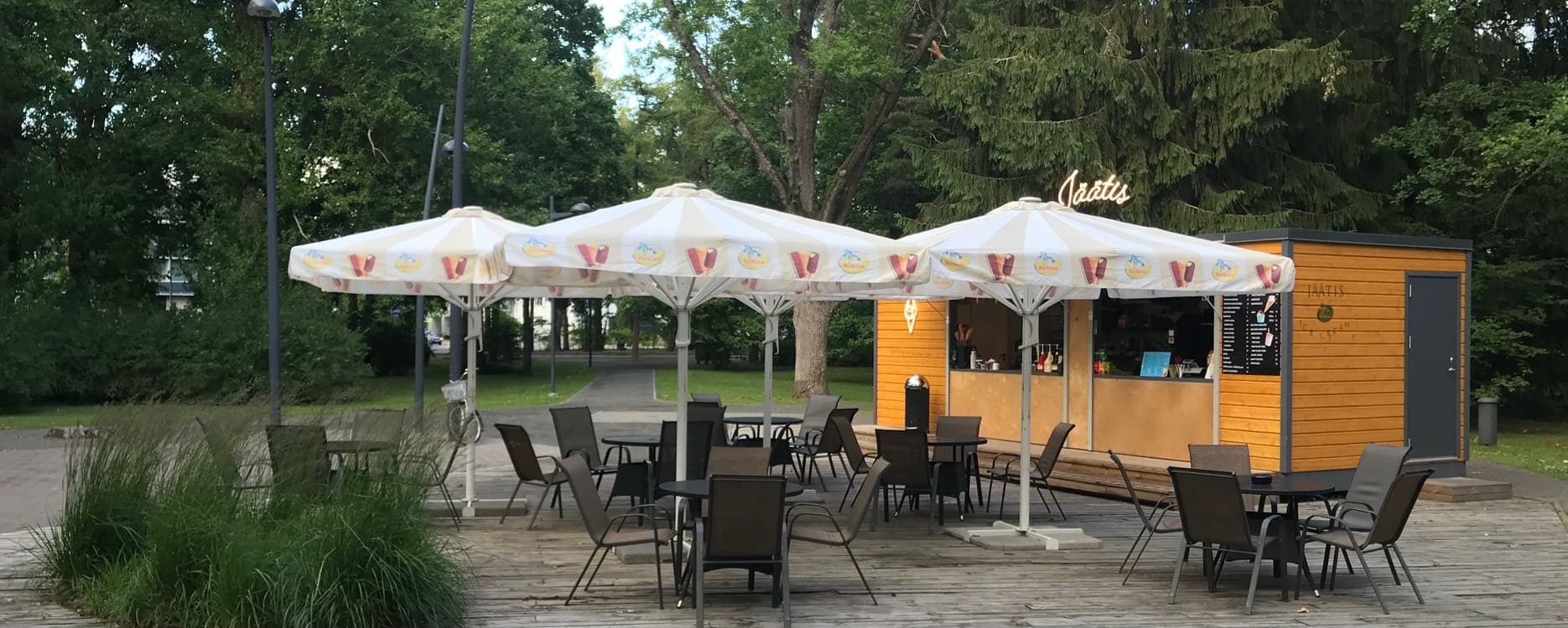 balts ulkoteltsaudums saulessargs punaisen ja keltaisen kuvioinnilla puistossa oranžssen kahvion