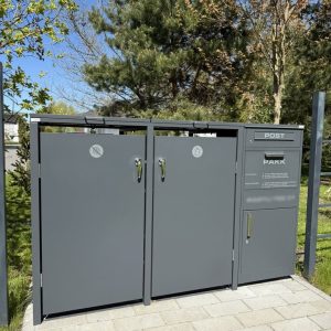 pelēks sopkärl med postlåda i trädgårdsmiljö
